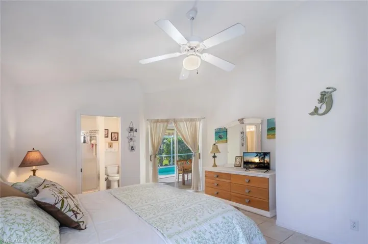 Bedroom featuring light tile patterned floors, connected bathroom, access to exterior, and a ceiling fan