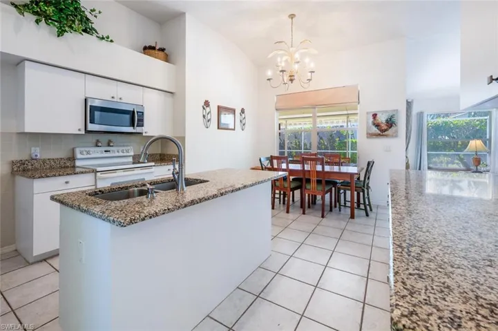 Kitchen with stainless steel microwave, light tile patterned floors, white cabinetry, white electric range, and a sink
