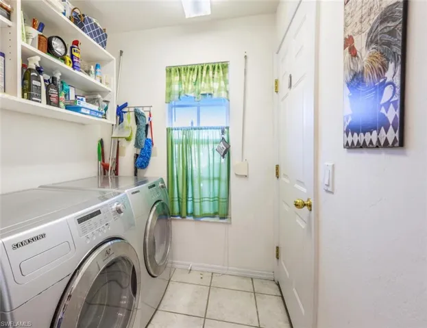 Laundry room with laundry area, light tile patterned floors, separate washer and dryer, and baseboards