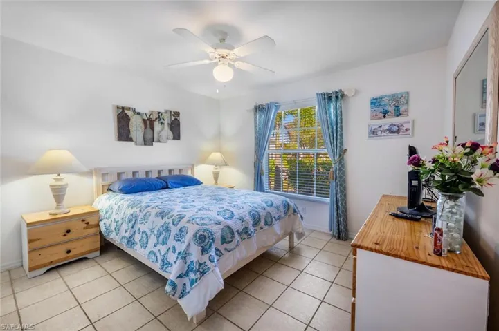 Bedroom with light tile patterned floors, baseboards, and ceiling fan