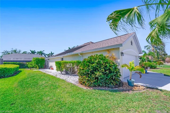 View of property exterior featuring stucco siding, driveway, an attached garage, and a yard