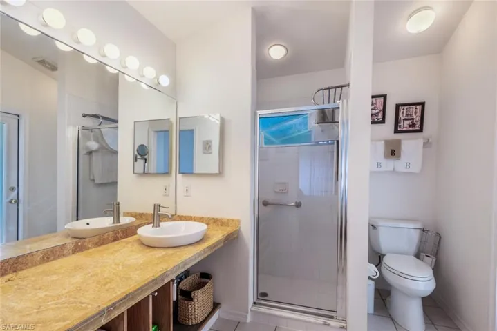 Full bathroom featuring vanity, visible vents, a stall shower, tile patterned floors, and toilet