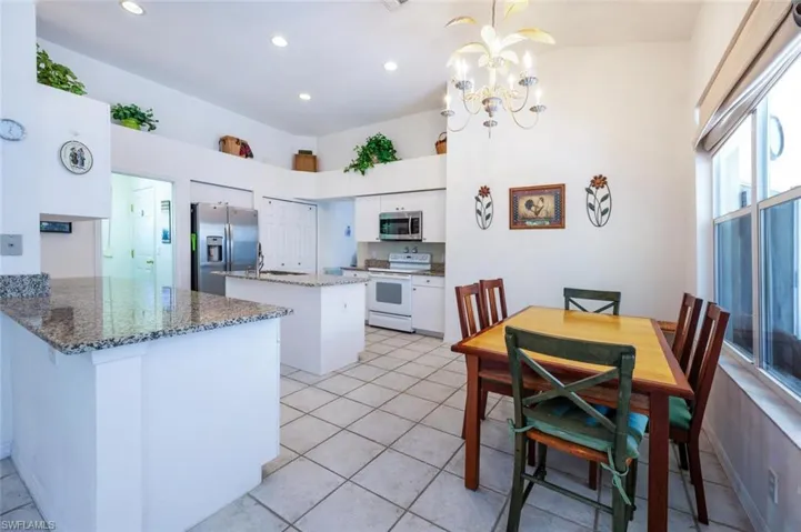 Kitchen featuring a peninsula, stone countertops, white cabinets, appliances with stainless steel finishes, and a center island