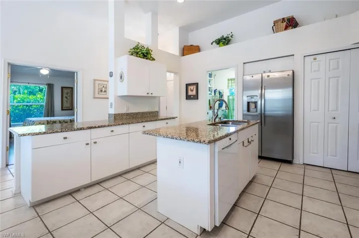 Kitchen with stainless steel refrigerator with ice dispenser, light tile patterned flooring, white dishwasher, white cabinets, and stone counters