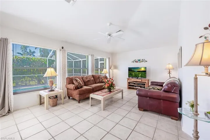 Living area with ceiling fan, visible vents, baseboards, and light tile patterned flooring