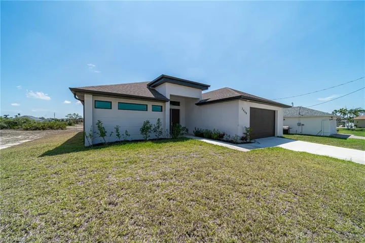 Prairie-style home with a front lawn, concrete driveway, stucco siding, a garage, and roof with shingles