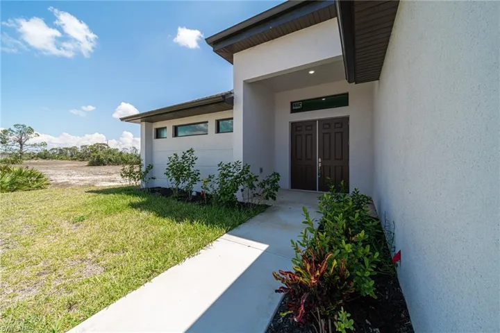 Property entrance with a lawn and stucco siding