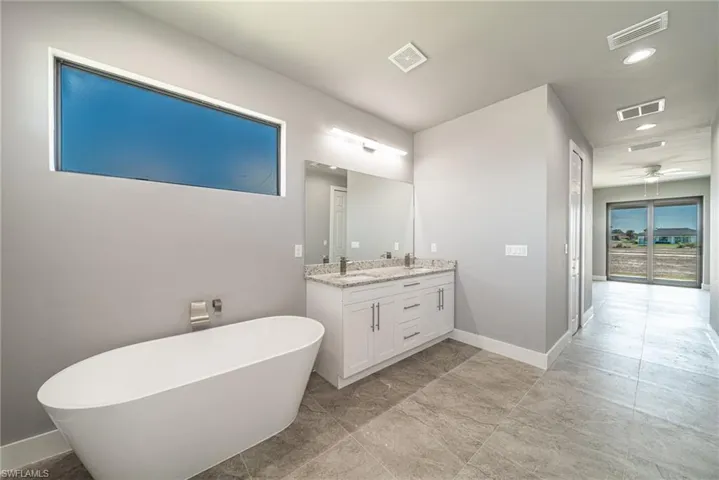 Full bath featuring double vanity, a freestanding tub, recessed lighting, and ceiling fan
