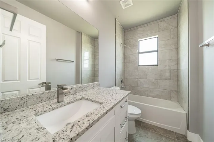 Bathroom featuring shower / tub combination, vanity, and light tile patterned floors