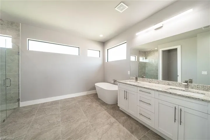 Full bathroom with a shower stall, double vanity, and a freestanding tub