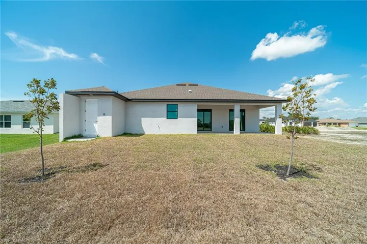 Back of house with a lawn, stucco siding, and a patio