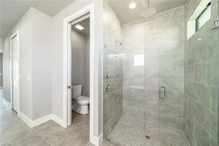 Bathroom featuring a shower stall and baseboards