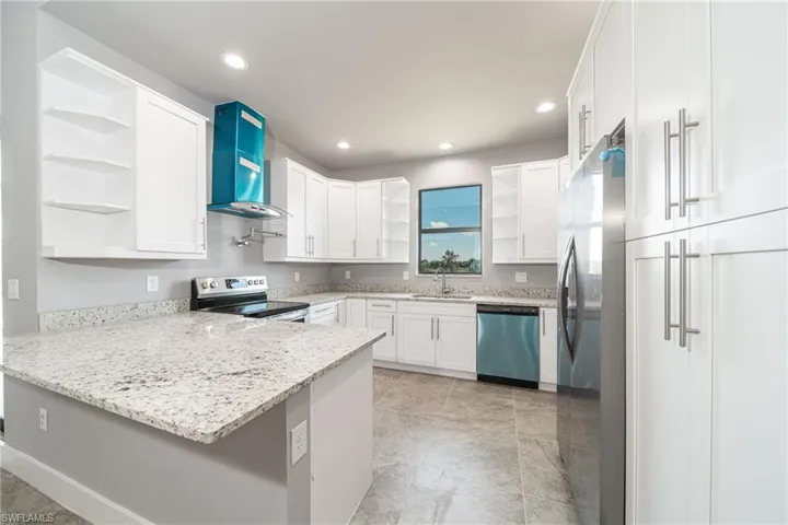 Kitchen featuring open shelves, a peninsula, light stone countertops, white cabinets, and recessed lighting