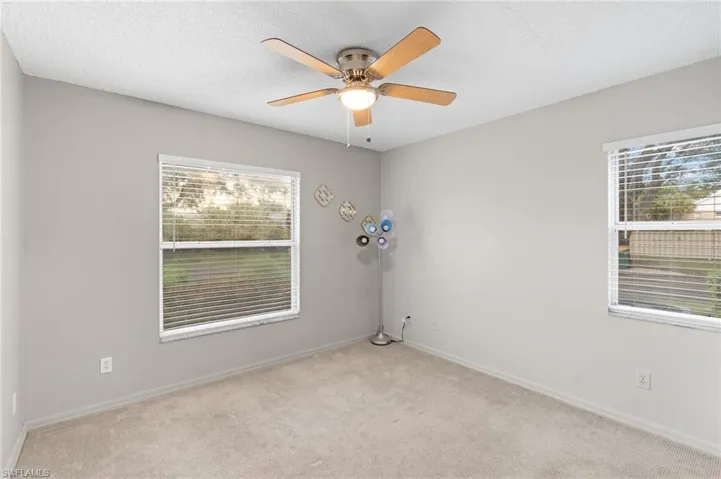 Unfurnished room with light colored carpet, a textured ceiling, plenty of natural light, and ceiling fan
