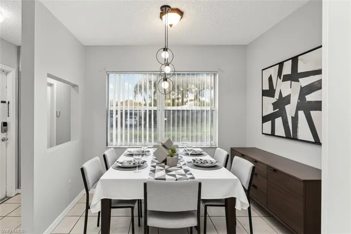 Dining area virtual staged featuring a textured ceiling, plenty of natural light, hanging lights, and light tile patterned flooring