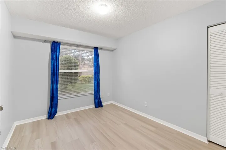 Empty room featuring light wood-type flooring and a textured ceiling