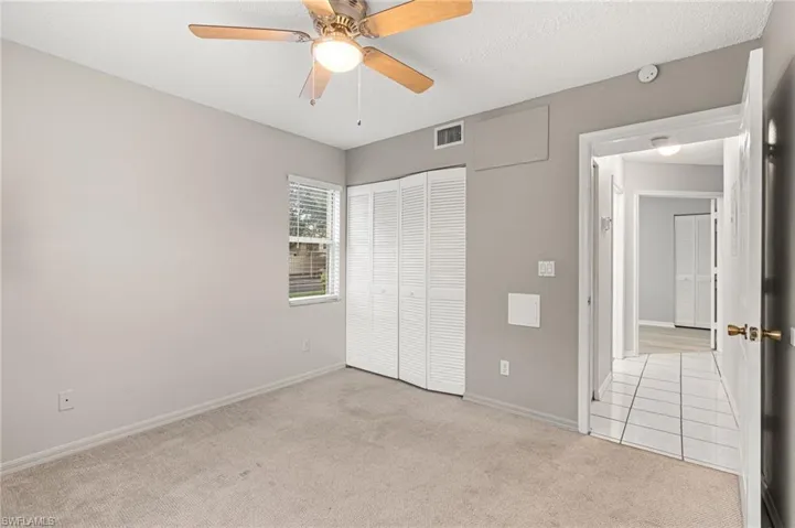 Unfurnished bedroom with light colored carpet, a textured ceiling, a closet, and a ceiling fan