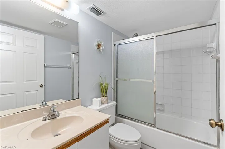 Full bathroom featuring vanity, a textured ceiling, and shower / bath combination with glass door