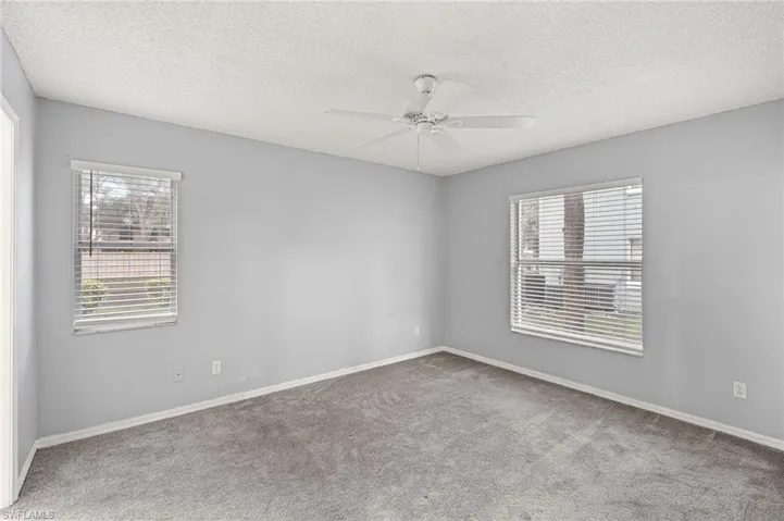 Unfurnished room with a textured ceiling, light colored carpet, and ceiling fan