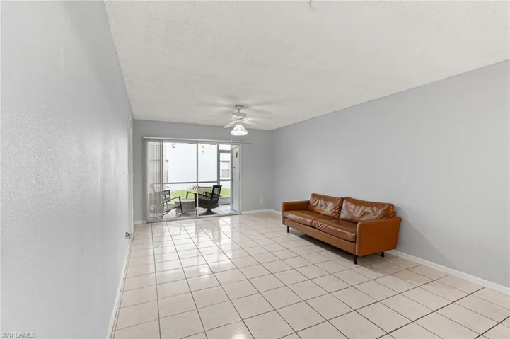 Living area with a textured ceiling, light tile patterned floors, and a ceiling fan