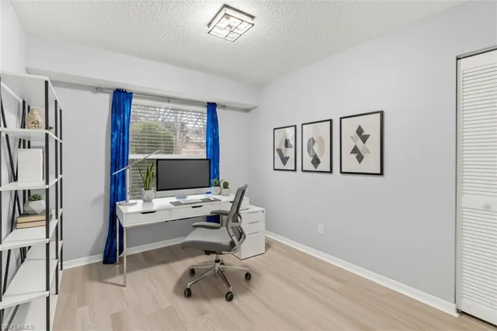 Home office virtual staged with light wood-style flooring and a textured ceiling