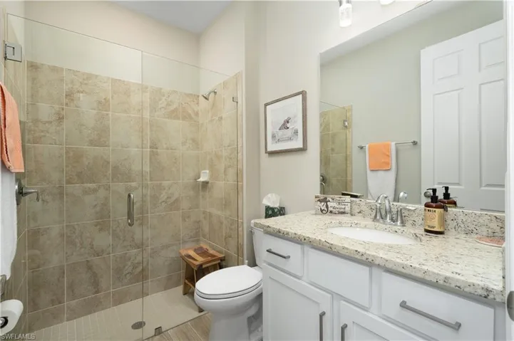 Bathroom featuring vanity, a shower with door, and toilet