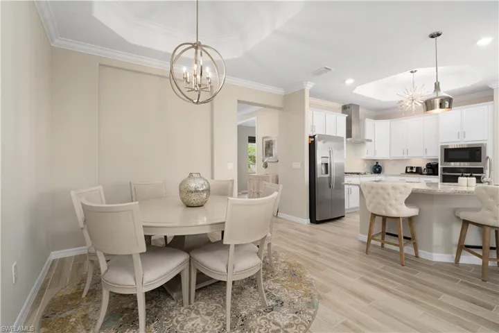 Dining space featuring a chandelier, crown molding, light wood-type flooring, and a tray ceiling