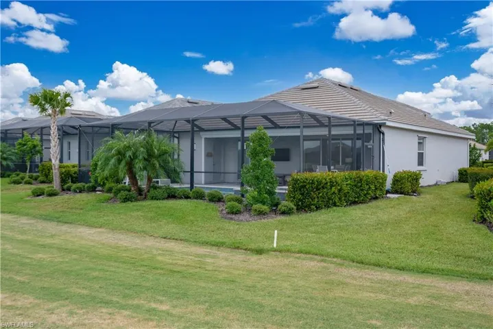 Back of house with glass enclosure and a yard