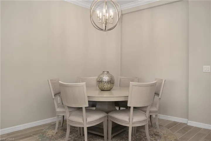 Dining area with light hardwood / wood-style floors, ornamental molding, and a chandelier
