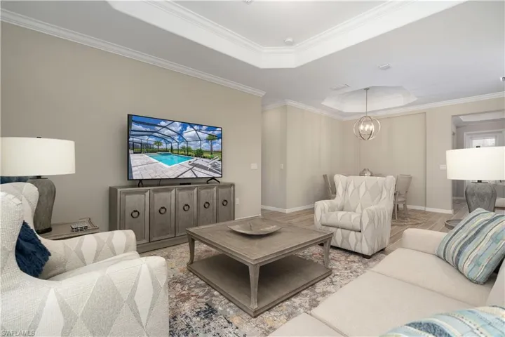 Living room with ornamental molding, an inviting chandelier, and a raised ceiling