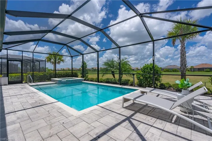 View of pool with an in ground hot tub, a patio, and glass enclosure