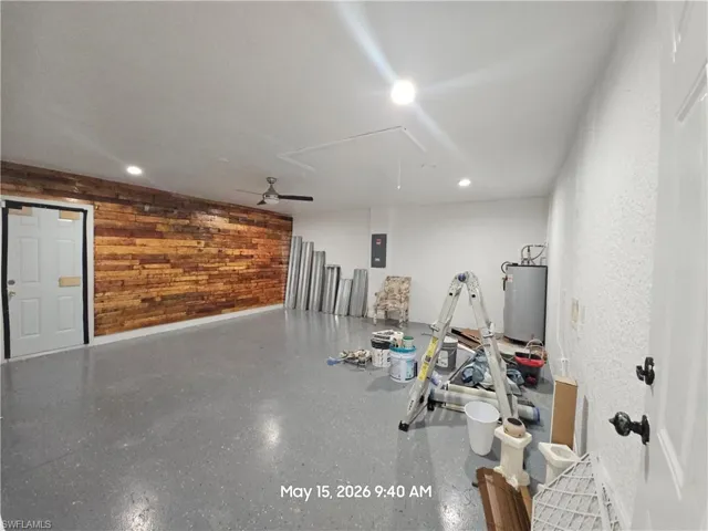 Spacious interior room featuring a wood-panel accent wall, gray epoxy flooring, recessed lighting, and a ceiling fan