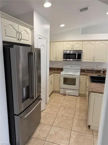 Kitchen featuring neutral-toned cabinetry, granite-style countertops, stainless steel microwave, and a breakfast bar