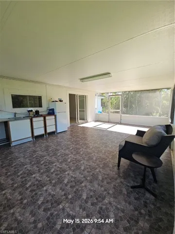 Spacious screened enclosure featuring a textured tile-patterned floor, a built-in countertop with cabinetry, and sliding glass doors