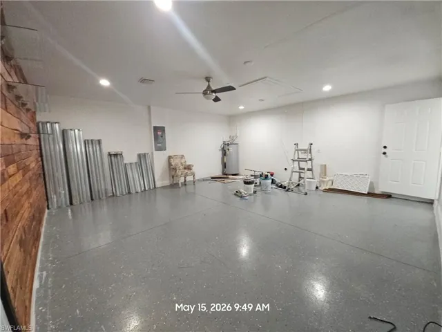 Spacious interior room with an epoxy-coated concrete floor, white painted walls, and a textured wood-finish accent wall