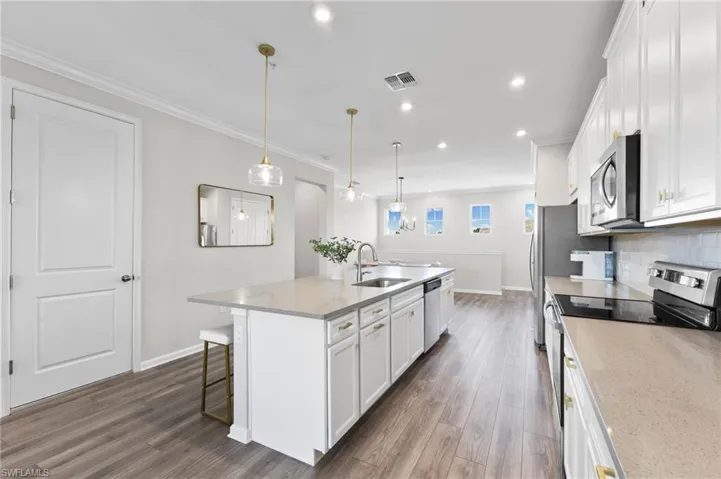 Kitchen with appliances with stainless steel finishes, a center island with sink, white cabinetry, a breakfast bar area, and recessed lighting