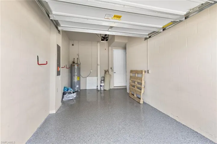 Garage featuring concrete block wall, electric water heater, and electric panel