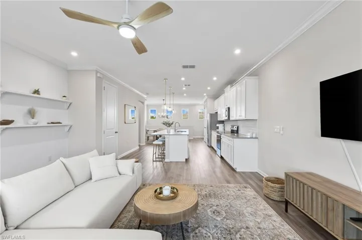 Living room with crown molding, ceiling fan, light wood finished floors, and recessed lighting
