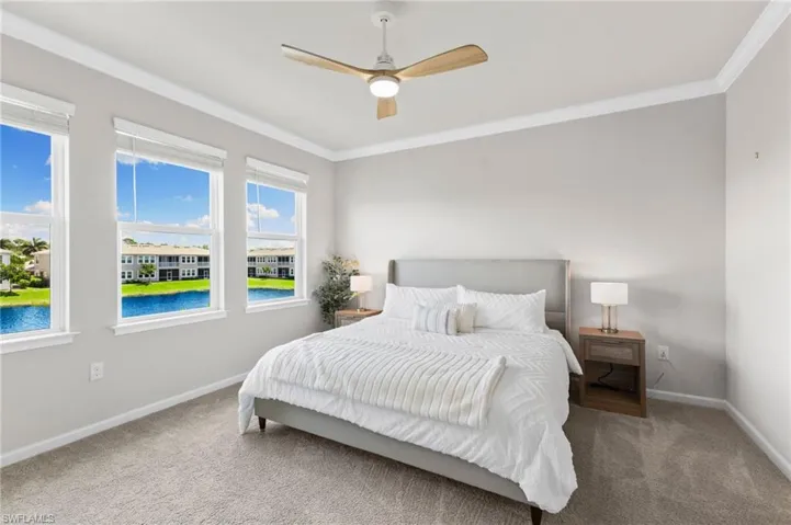 Bedroom featuring crown molding, a water view, carpet, and ceiling fan