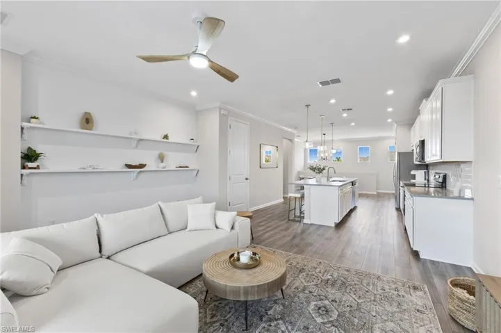 Living room with crown molding, light wood-type flooring, recessed lighting, and ceiling fan