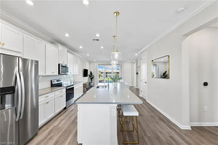 Kitchen featuring stainless steel appliances, a center island with sink, white cabinetry, a breakfast bar area, and recessed lighting