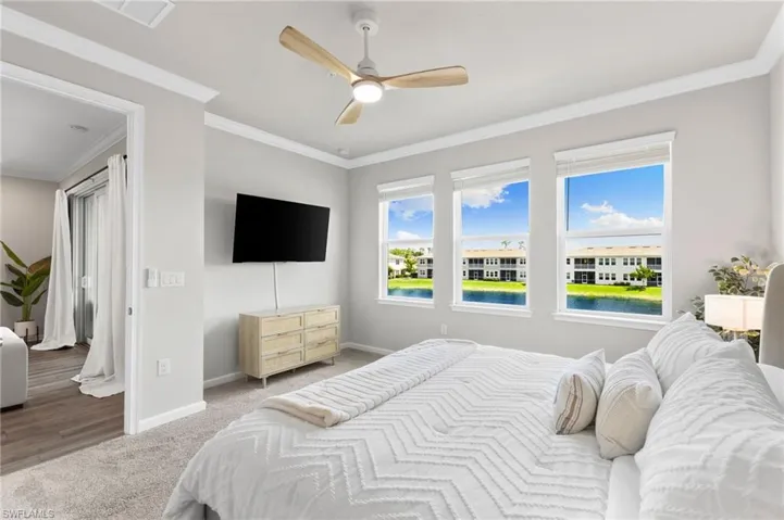 Carpeted bedroom with ornamental molding and ceiling fan