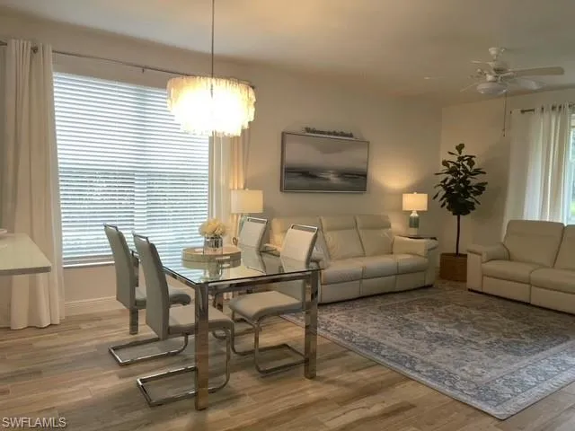 Dining area featuring light wood-type flooring, a ceiling fan, and a chandelier