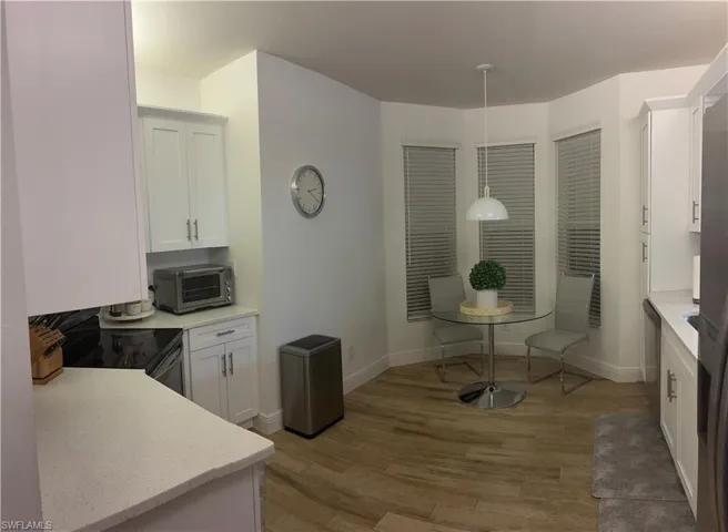 Kitchen featuring eat in breakfast area, pendant lighting, white cabinetry, light wood finished floors, and electric range oven