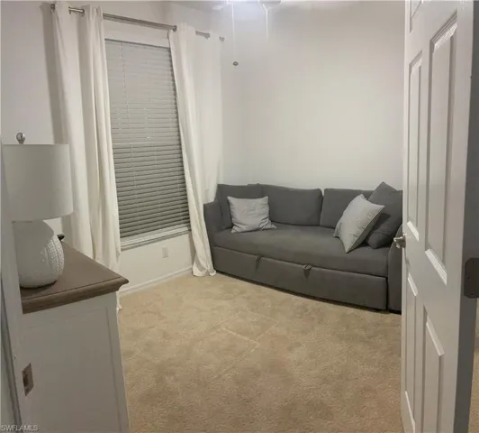 3rd bdrm furnished as den/office featuring light colored carpet and baseboards