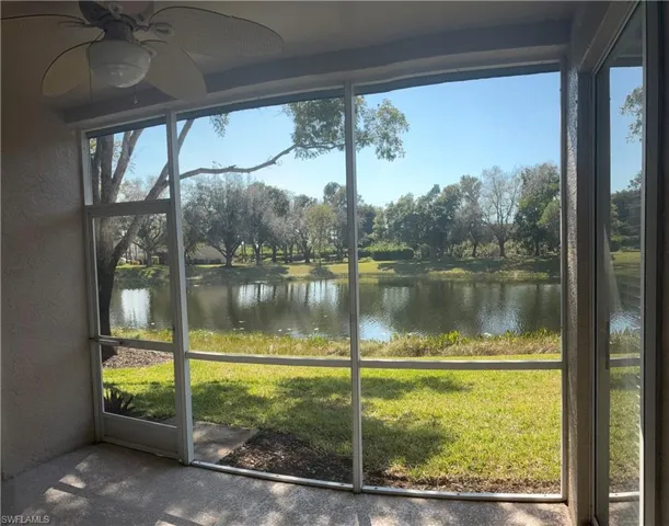 screen lanai featuring lake view, hurricane shutters and ceiling fan and electric hurrican shutters and ceiling fan