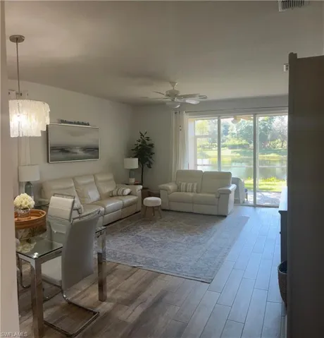 Living room featuring a water view, wood finished floors, ceiling fan, and hanging lights