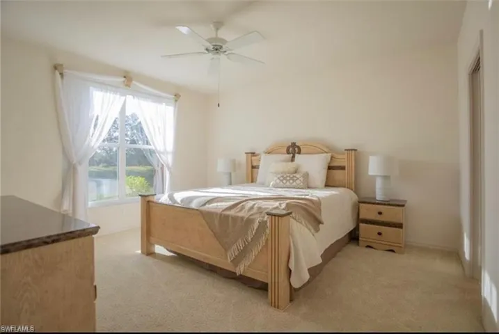 Primary Bedroom with light colored carpet and ceiling fan