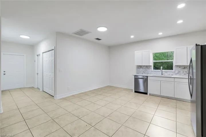 Kitchen with white cabinets, stainless steel appliances, tasteful backsplash, light tile patterned floors, and recessed lighting