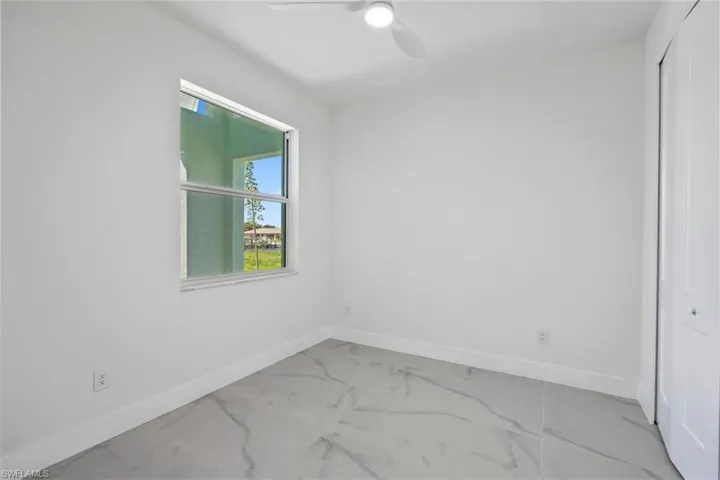 Unfurnished room featuring ceiling fan, marble finish floor, and baseboards